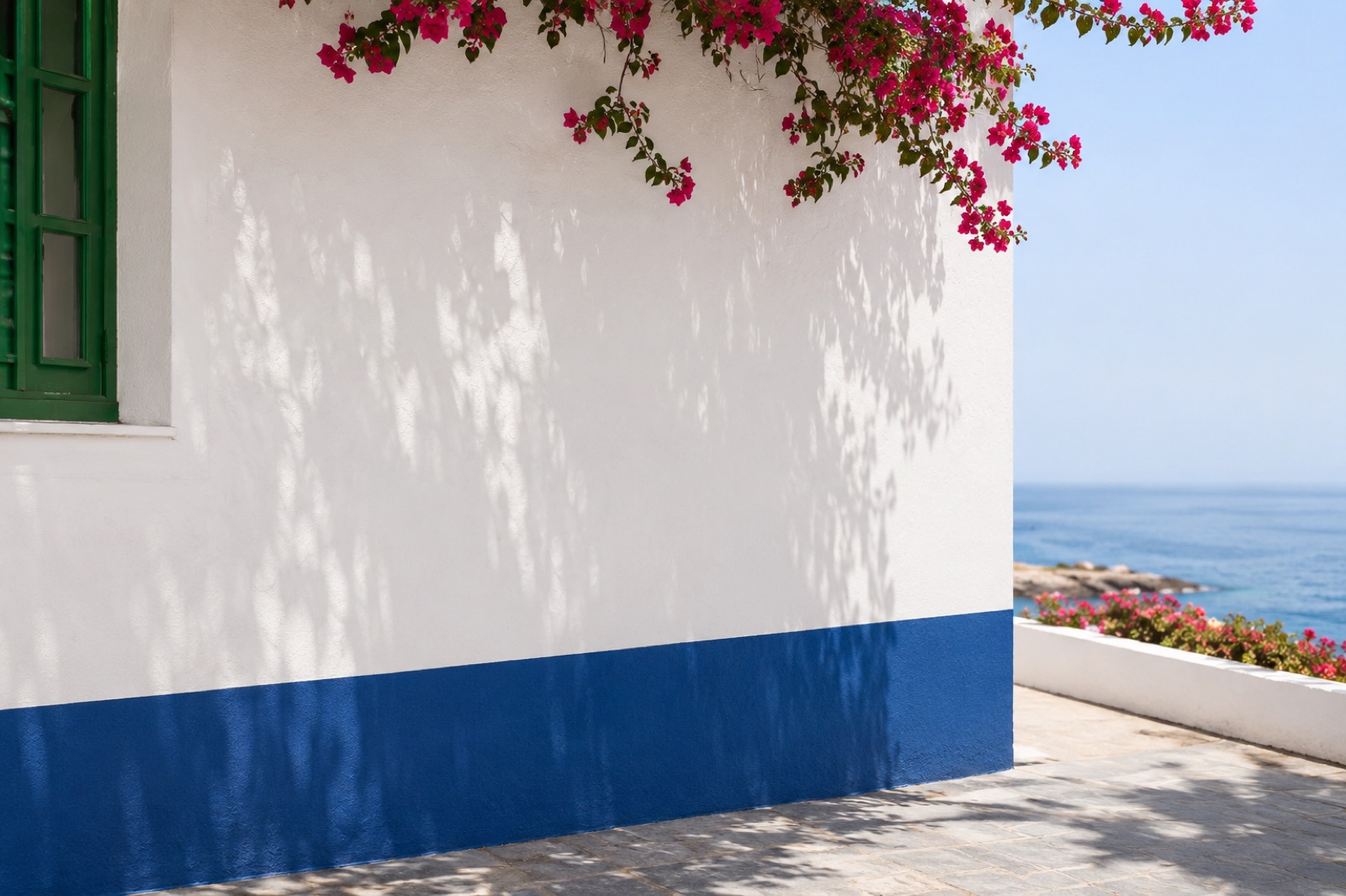 Pared encalada con franja azul, buganvilla y el mar Atlántico de fondo